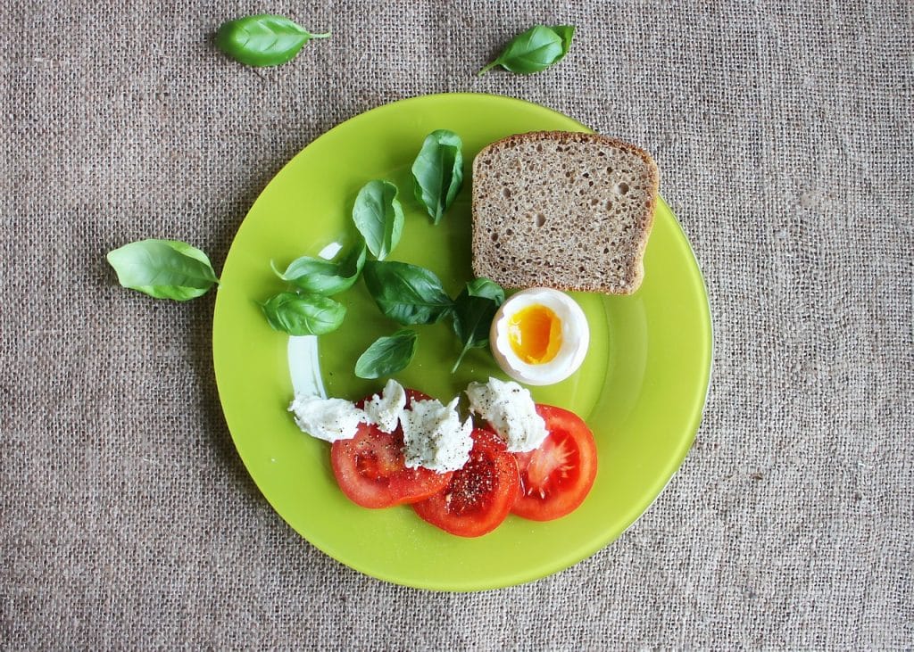 Une assiette de petit déjeuner équilibré qui comporte des oeufs, des tomates, de la salade, du pain complet , idéal pour une perte de poids saine sans régimes et sans frustrations