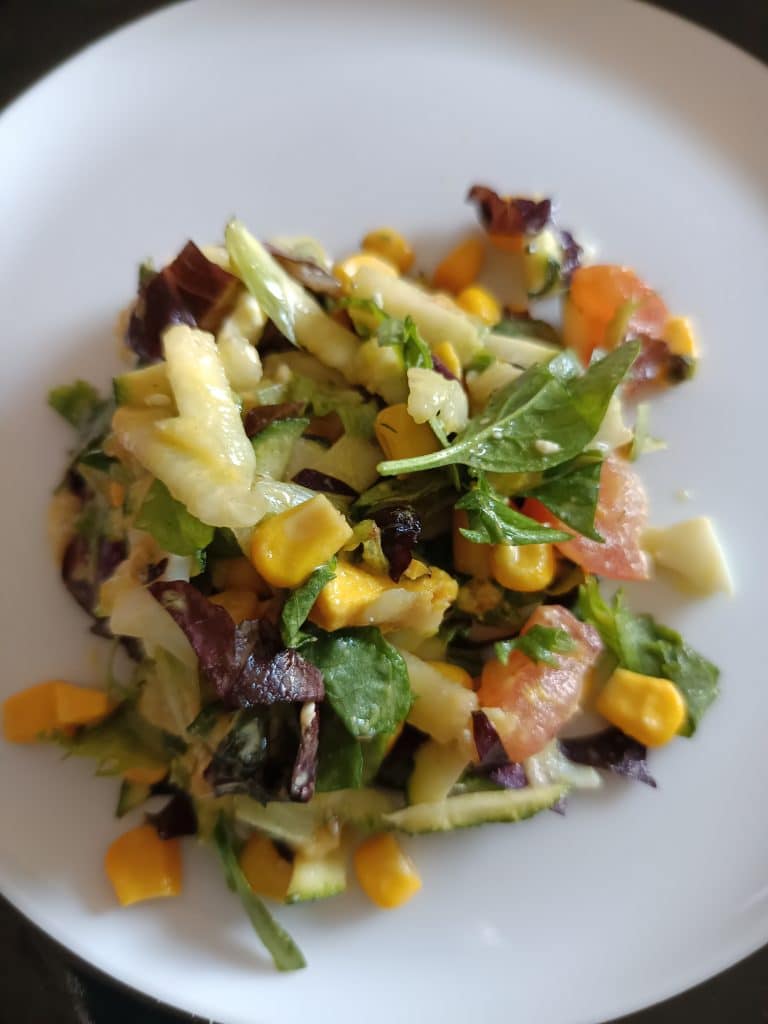 Une assiette de crudités avec de la salade, du céleri, du hareng fumé, du maïs