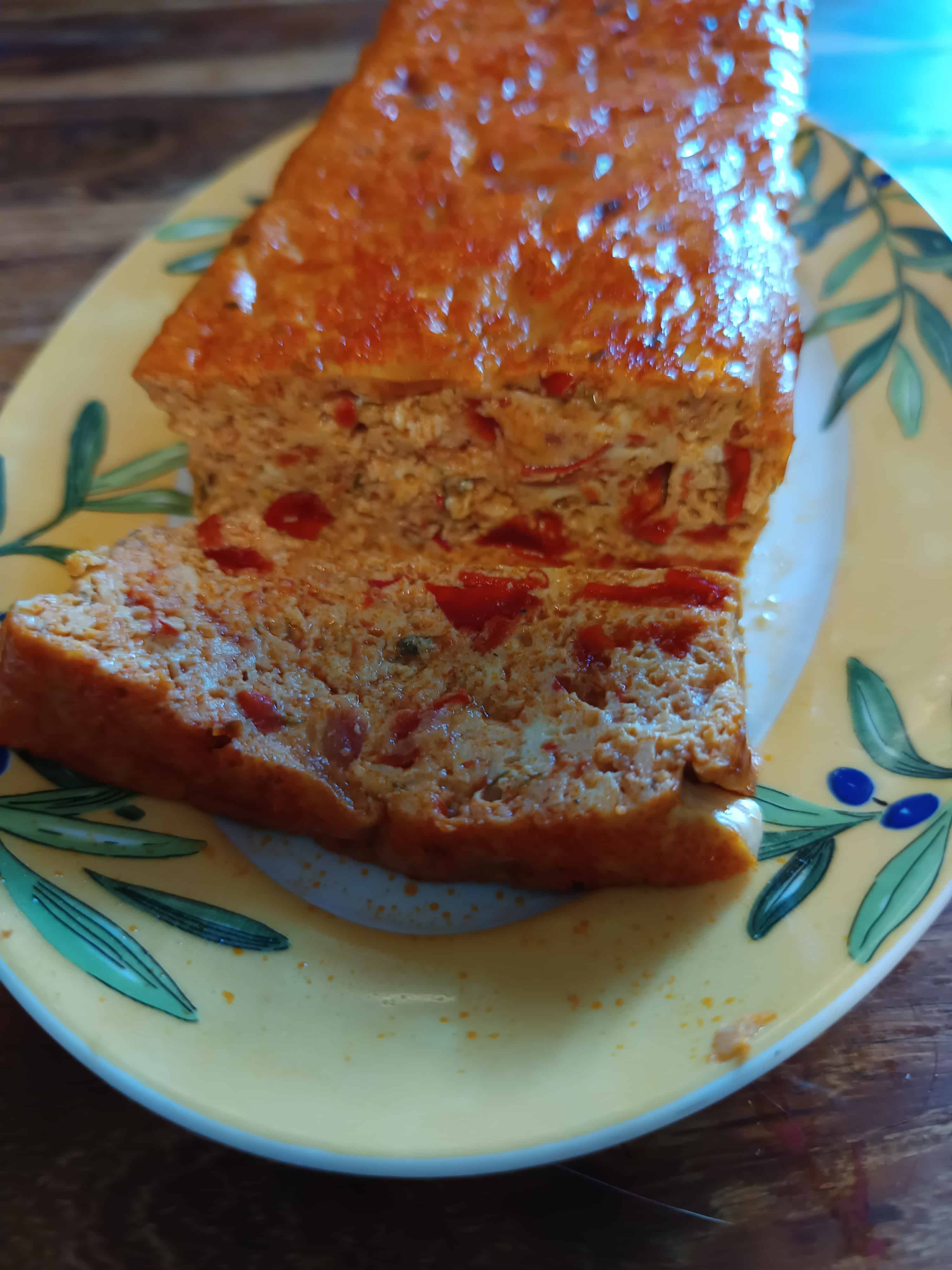 Un plat dans lequel est posé un pain de poivron et une tranche découpée de ce pain